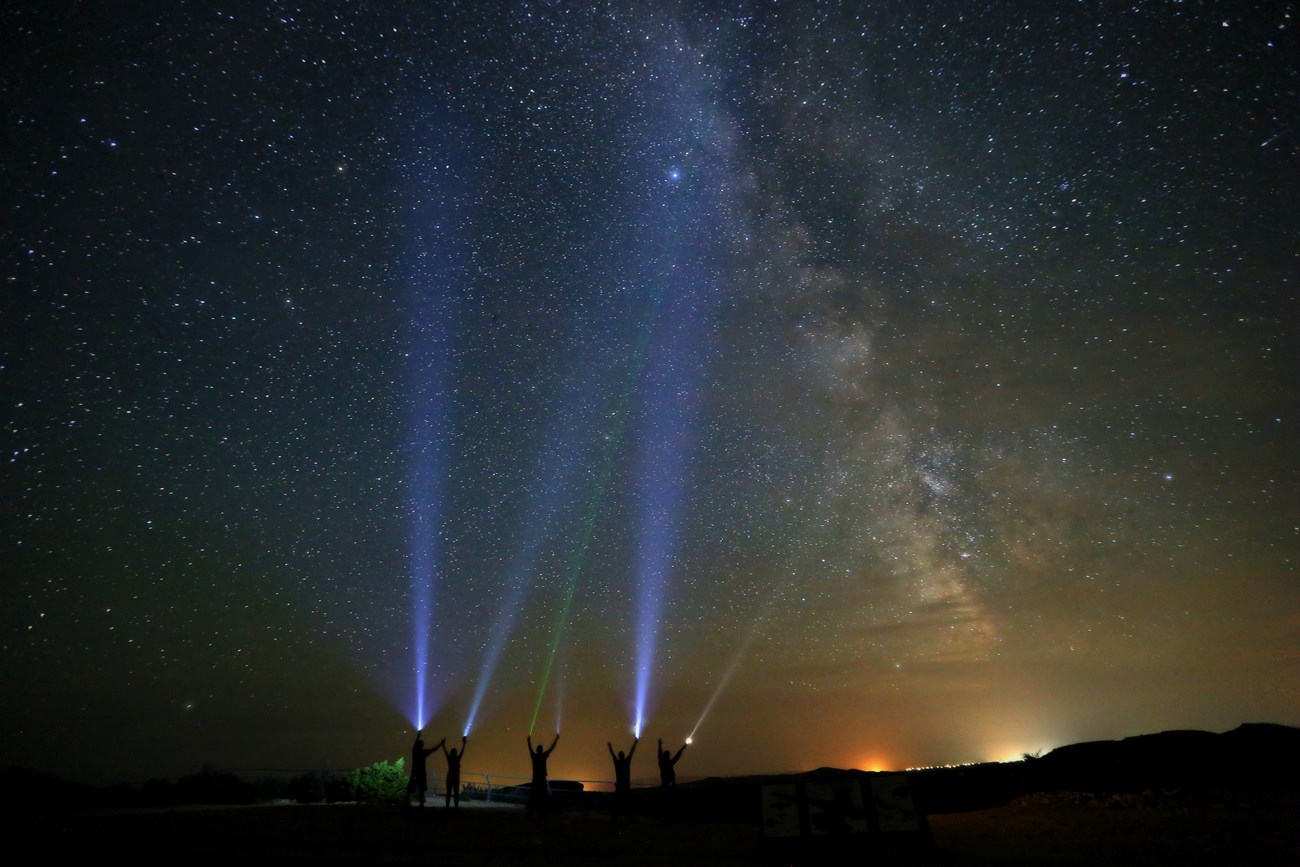 5 people shine flashlights into the night sky at Devil Canyon Overlook.