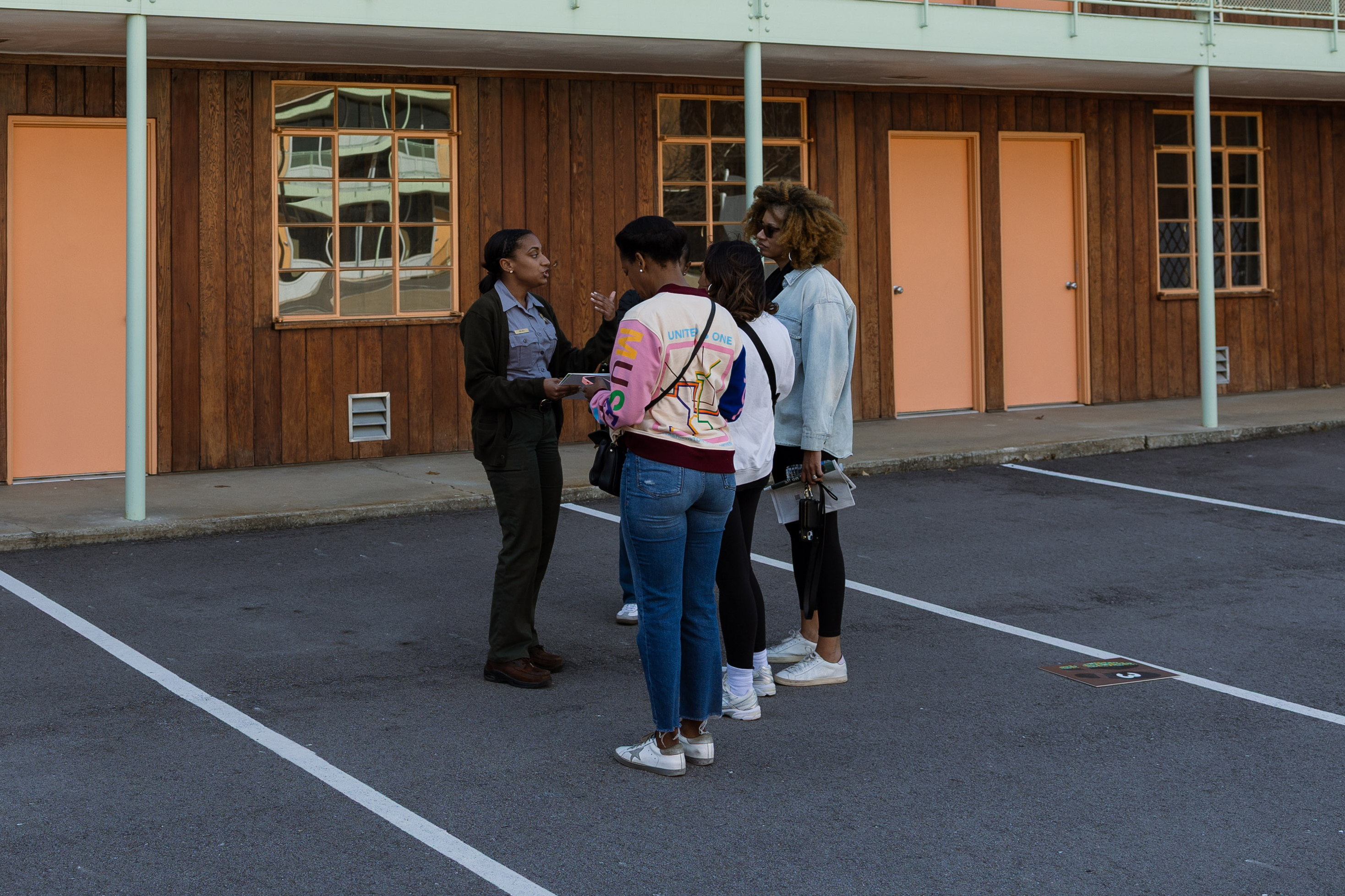 A ranger stands in front of a 1950s motel talking to two visitors,