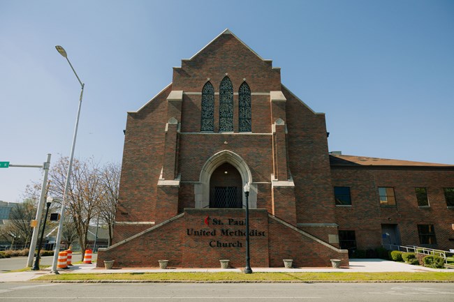 A brick church with stained glass windows and wide entrance.