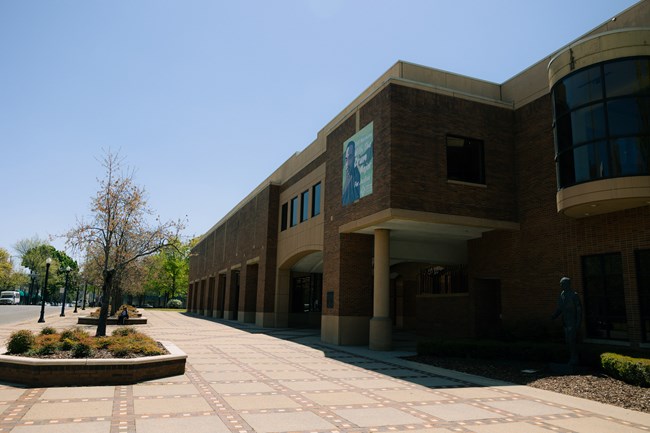 A side view of a brick and concrete building with a decorative sidewalk in front.