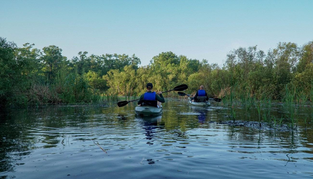 two kayakers paddle through a waterway