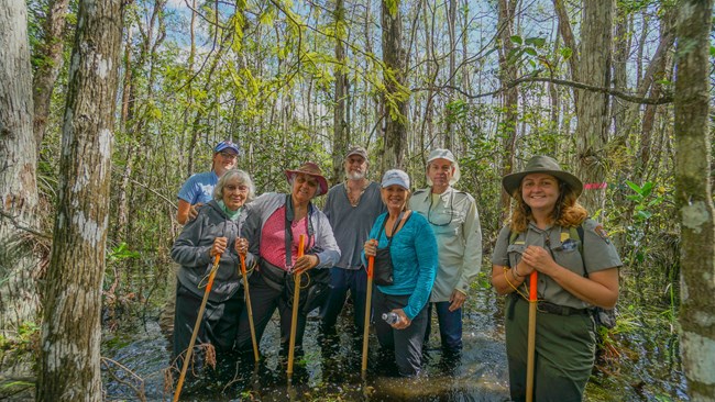 A female ranger standing with a group of people in a wet cypress tree swamp.