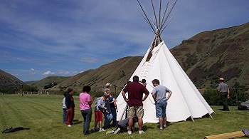 A group of people help two rangers set up a tipi.