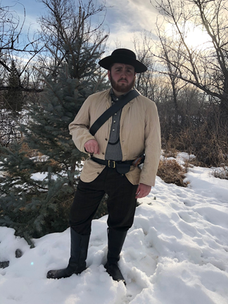 Austin Haney in period dress standing in front of trees in the snow