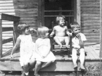 Small children sitting on a front porch.