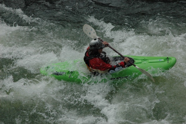 Kayaker maneuvering through rapids in river