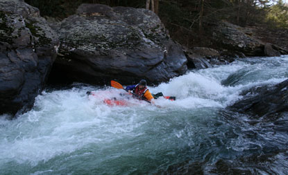 paddler maneuvering through rapid on river