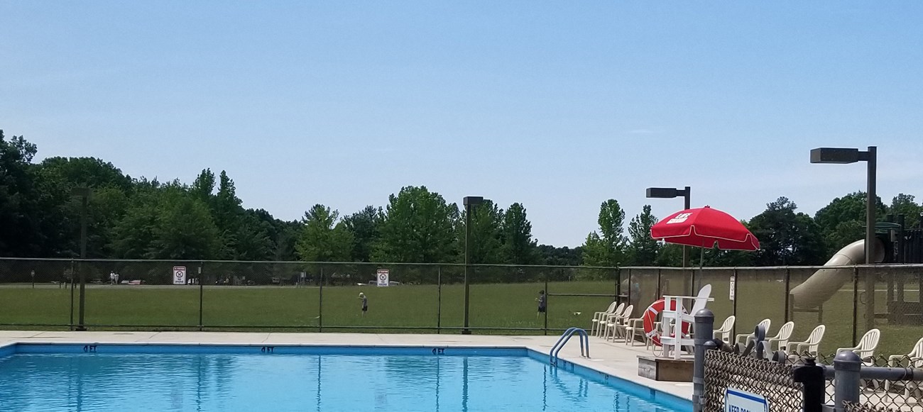 Lifeguard chair sits on edge of clear blue pool