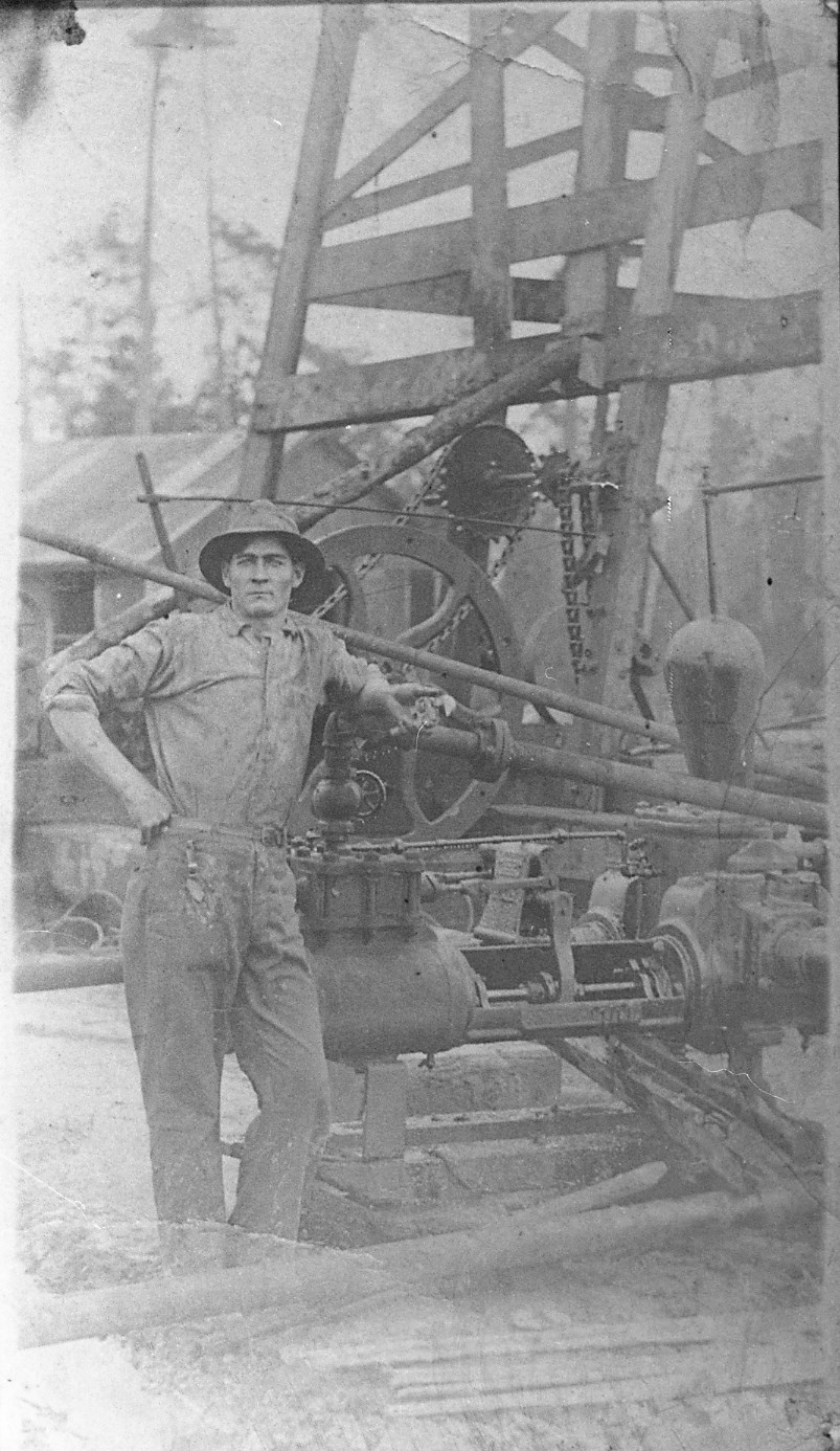 old photo of man leaning on machinery on oil derrick