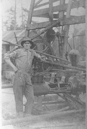 old photo of man leaning on machinery on oil derrick