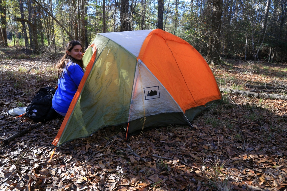 woman sitting next to a tent in the forest