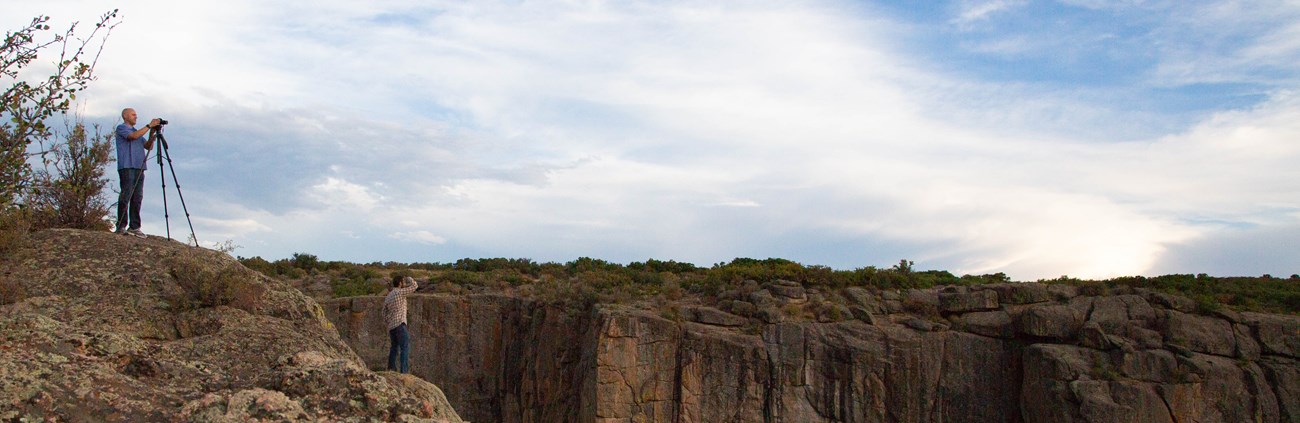 Visitors taking photos from an overlook by a large, deep canyon