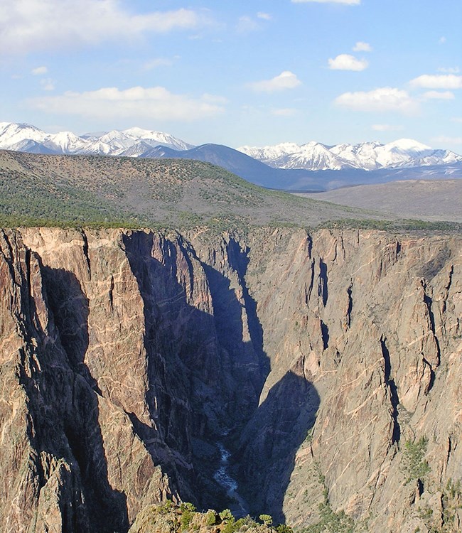 snow-capped mountains in the background, canyon with river in the foreground