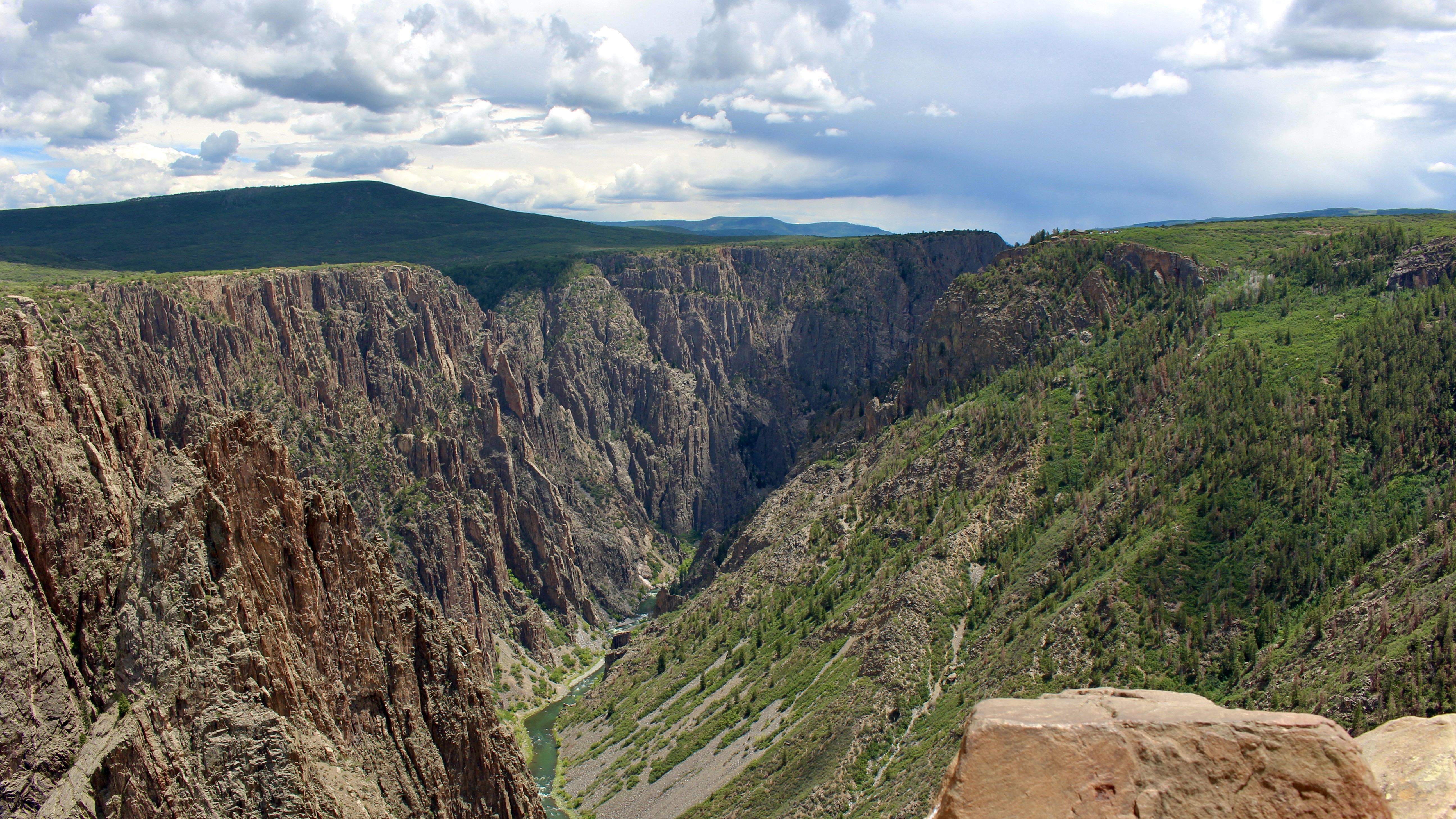 A view of a steep deep canyon with dark walls and greenery