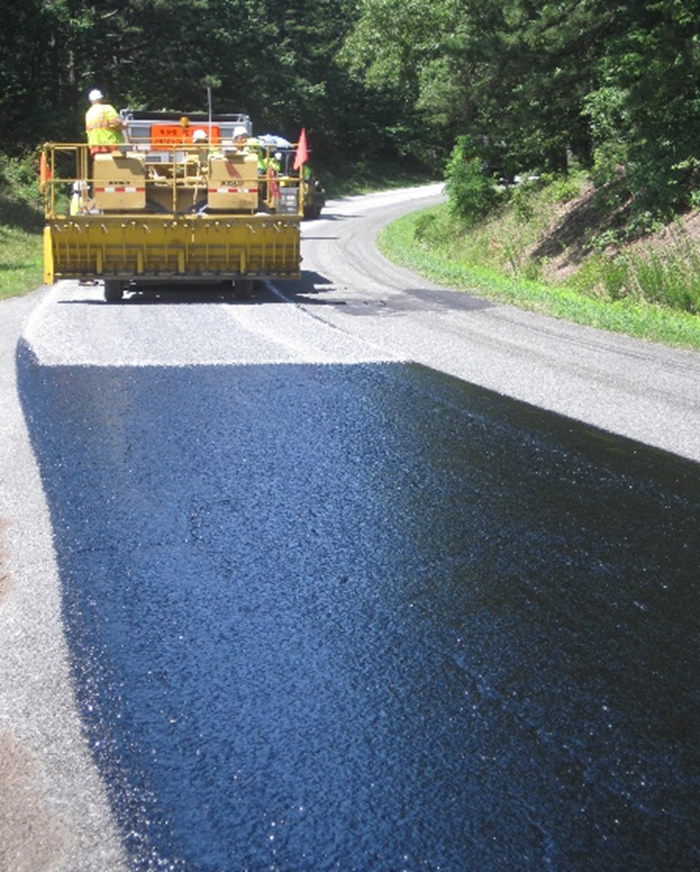 The steps involved in the chip and fog seal process include cleaning and prepping, chip seal application and curing, vacuuming to reduce loose gravel, fog sealing and striping, and repeating the process in the next section of project zone. NPS Photo