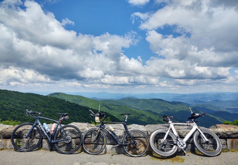 Three bikes rest against a stone wall at an overlook