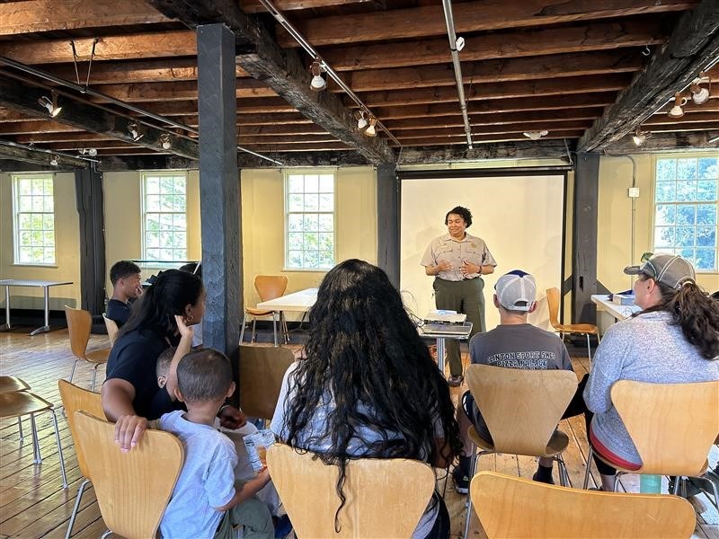 Group of students and adults seated listening to Ranger