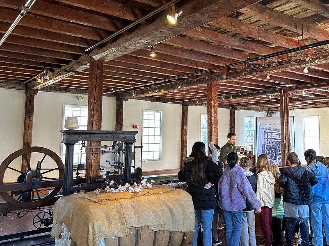 Group of students standing next to cotton bale and machines listening to Ranger talk