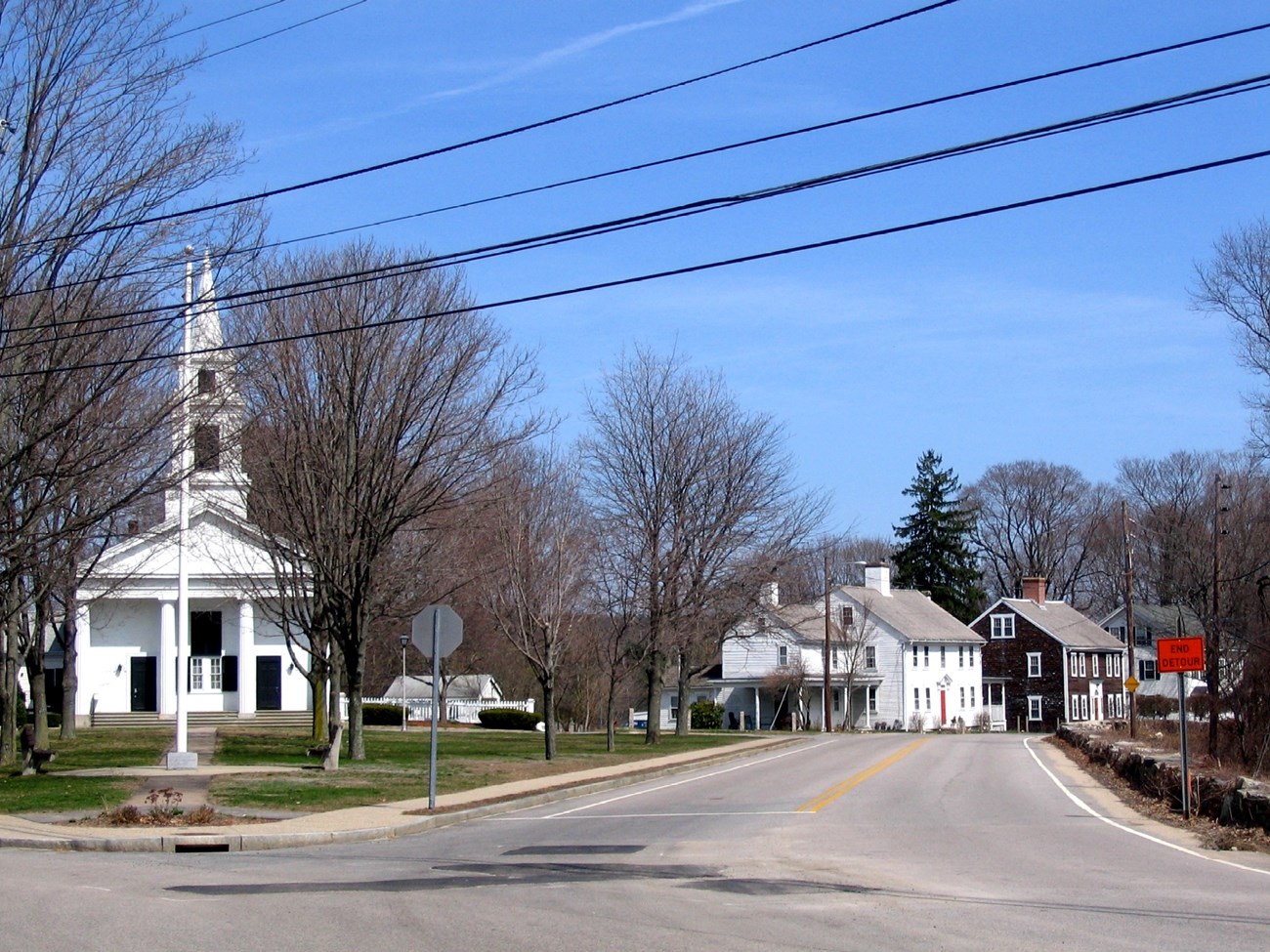 White Church with columns and steeple next to 3 2 1/2 story houses