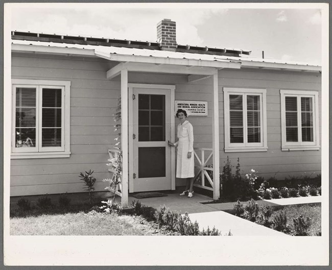 a female nurse stands in front of a house
