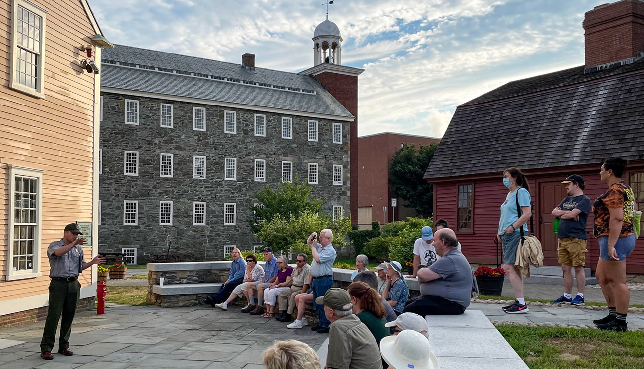 Park Ranger giving a tour to visitors in front of Slater Mill