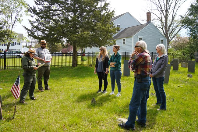 Two Rangers standing in cemetery with group of visitors