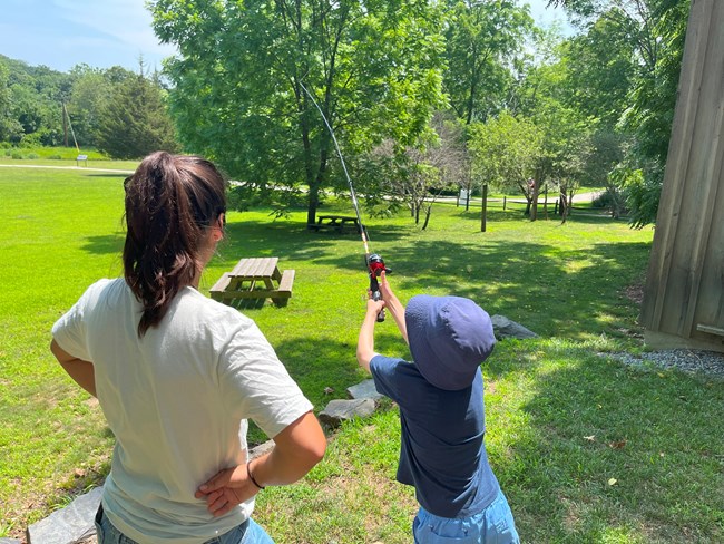 Intern standing next to young boy holding a fishing pole