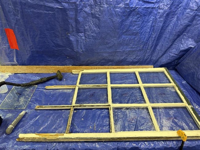 Window frame sits on blue tarps