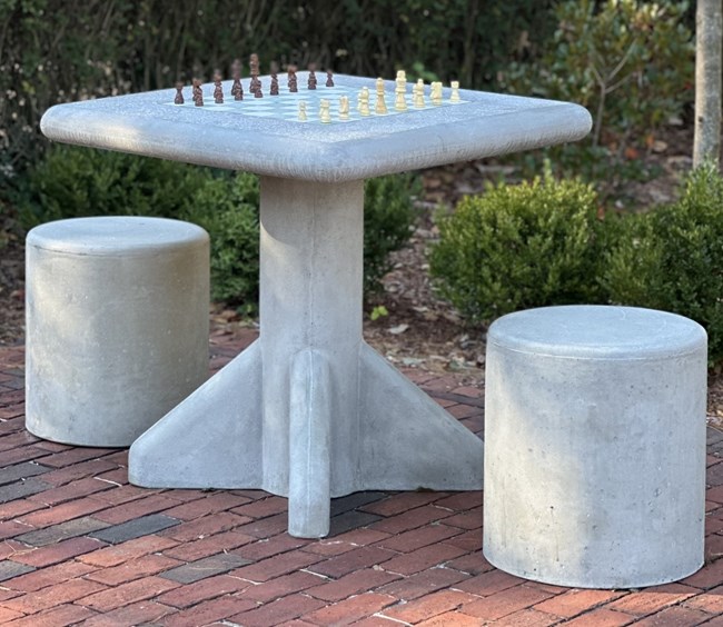 Outdoor chess table with two stools on brick path