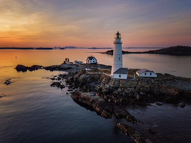 View of a lighthouse on a small island amidst a sunset