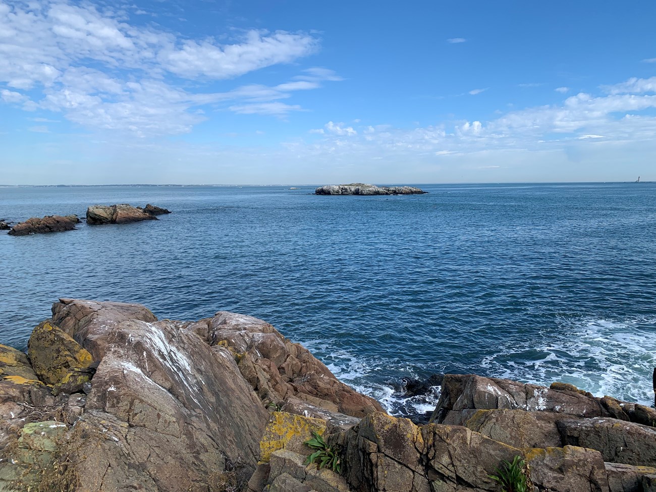 looking over a rocky shore to a small rocky outcropping of an island.