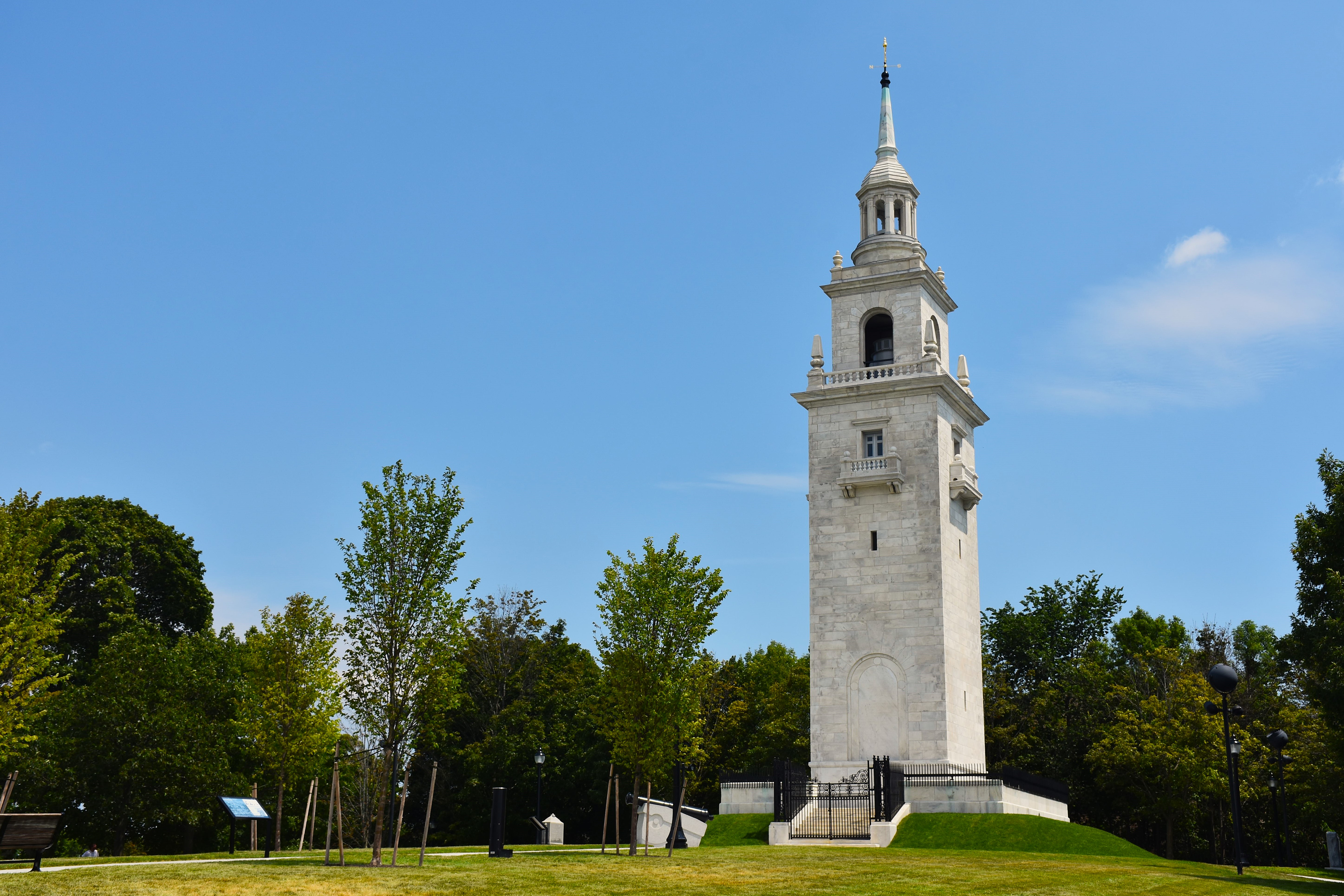 Tall granite monument tower rises above grassy grounds