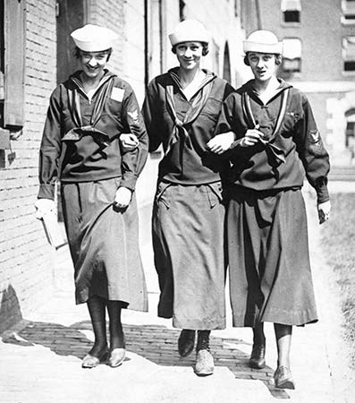 Black and white photgraph of three women walking through the navy yard in their "Yeomanette" uniforms