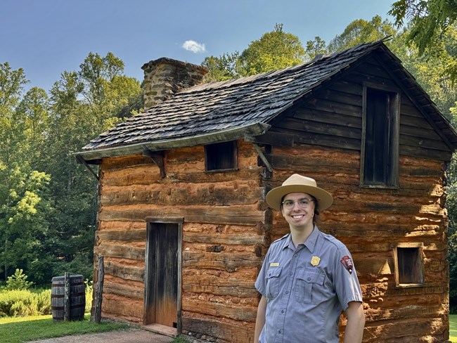 A park ranger stands in front of the reconstructed Kitchen Cabin