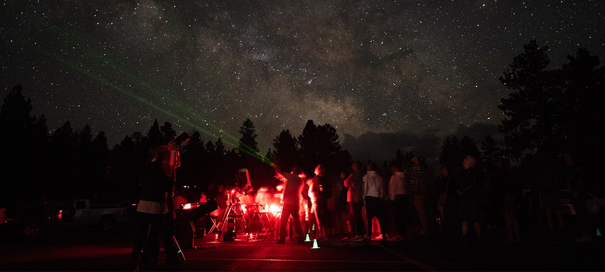 a group of people stargaze, illuminated by red lights