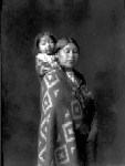 Indian woman in blanket, with small child on back by J.A. Shuck.