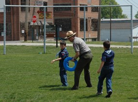 Superintendent Dennis Vasquez plays a game with two boy scouts on the historic playground with the historic backstop in the background during a previous Scouting Day.
