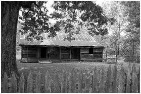 black & white photo of Collier Homestead cabin with paling fence in foreground