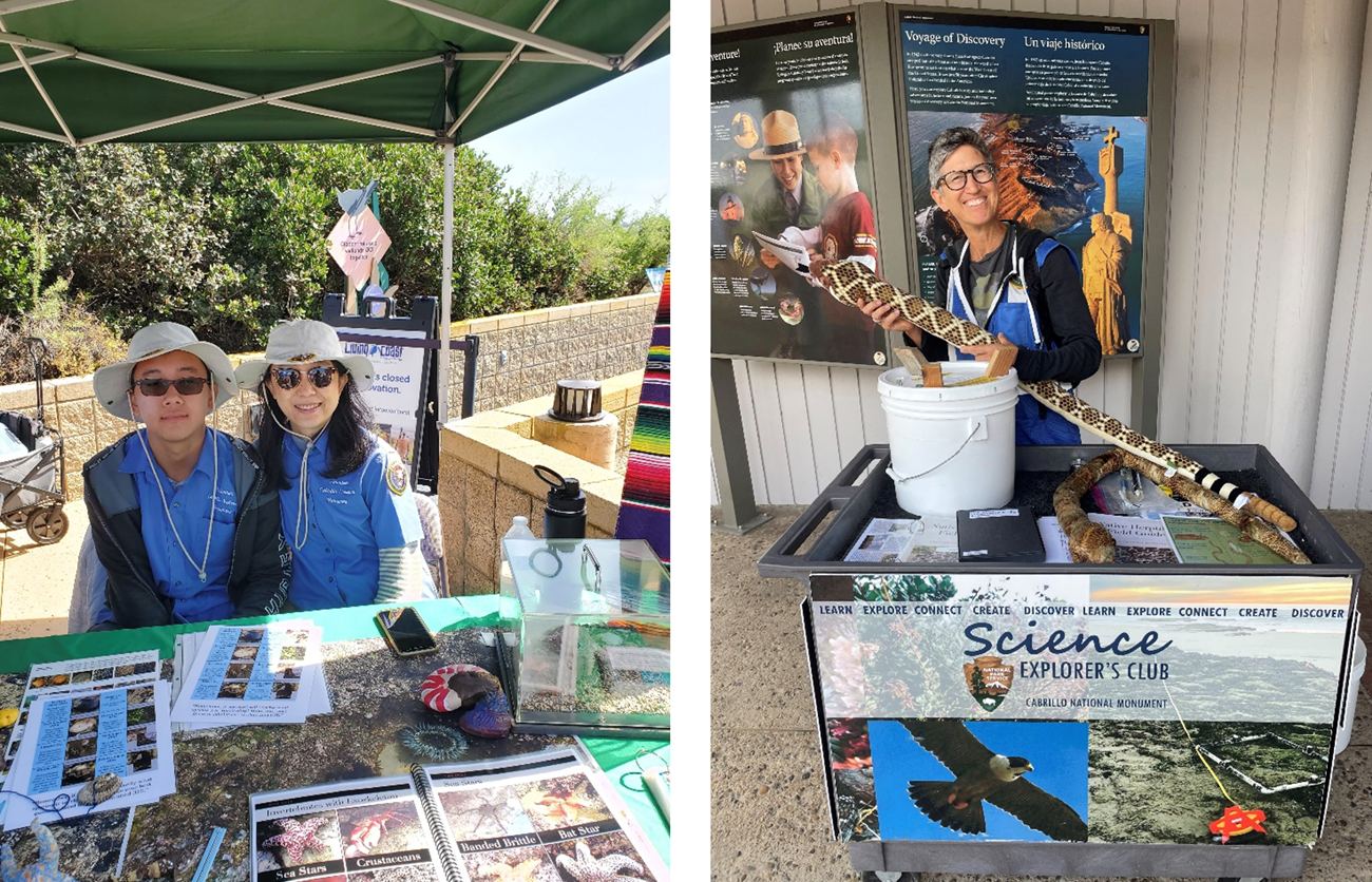 An adult and youth pair of Science Explorer’s Club volunteers sit behind an activity table, A volunteer holds a giant stuffed rattlesnake toy