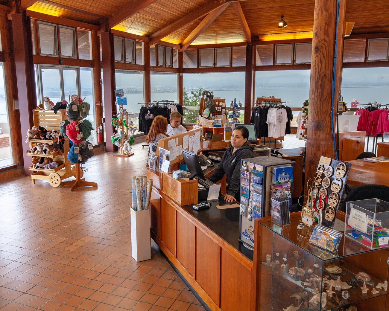 Inside the visitor center. Books, gifts, clothes and a front desk with people.