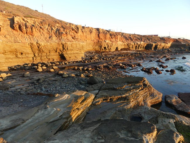 A rocky shoreline along sandstone cliffs.