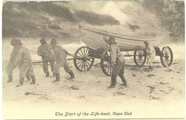 A group of men stand around a boat about to launched to sea.