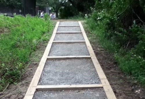 Steps on a trail are resurfaced with fresh wood planks and gravel.
