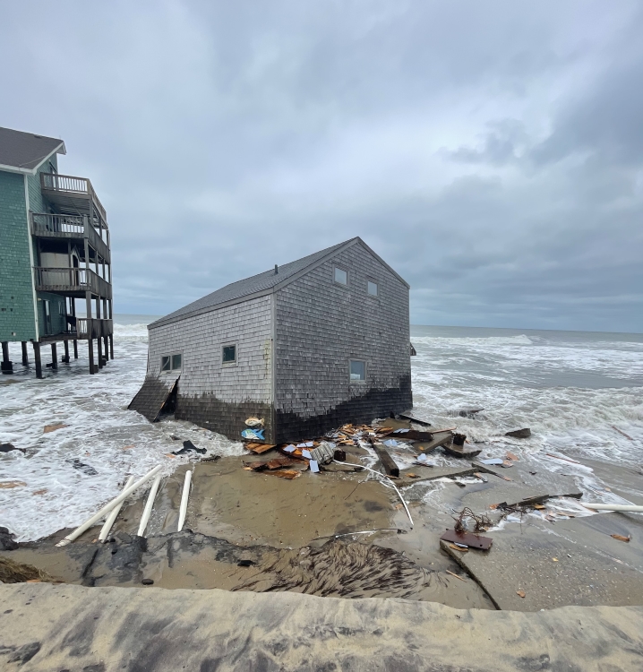 Photo of collapsed house on beach near the ocean.