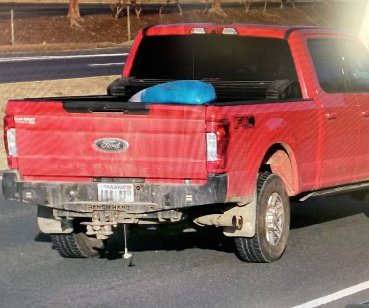 Image of a red truck carrying a blue and white kayak.