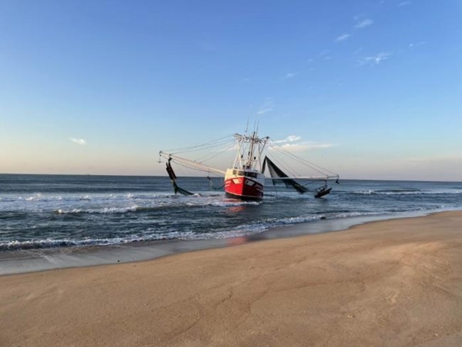 Grounded red and white vessel near the beach.