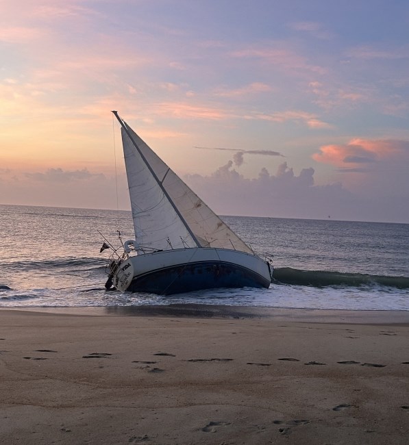 Photo of white vessel grounded on beach.