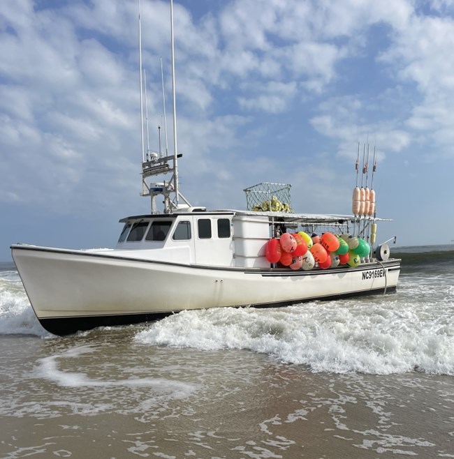 Photo of white vessel grounded on beach.