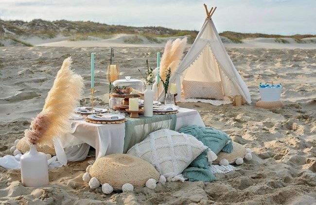 Beach picnic with table, pillows and blankets