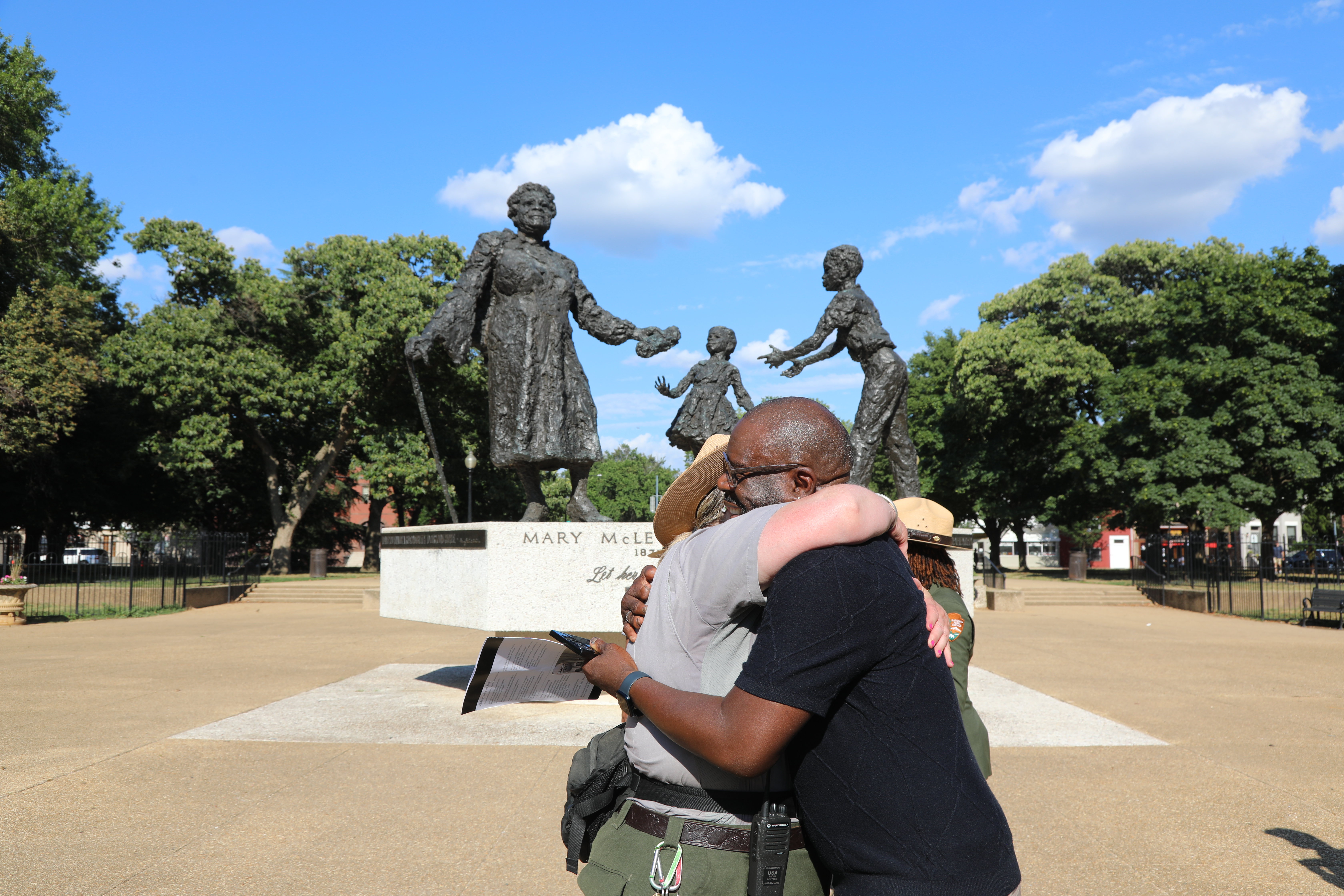 A park ranger and volunteer embrace in front of the Mary McLeod Bethune Memorial in Lincoln Park, Washington, D.C.